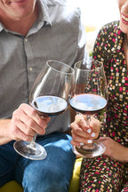 Smiling couple toasting with glasses of 2020 HALL Craig's Cabernet Sauvignon
